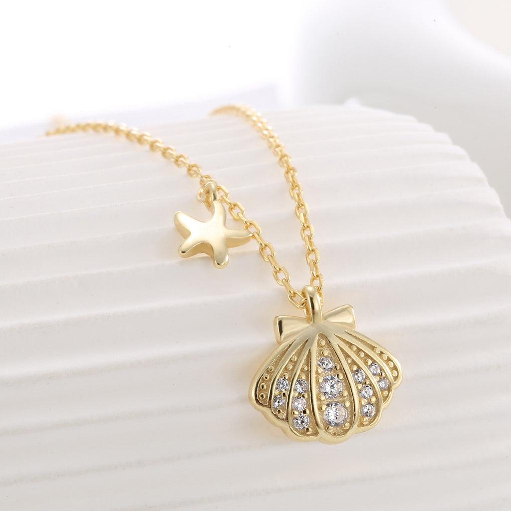 close view of clear-stone seashell pendant on fine gold plated chain