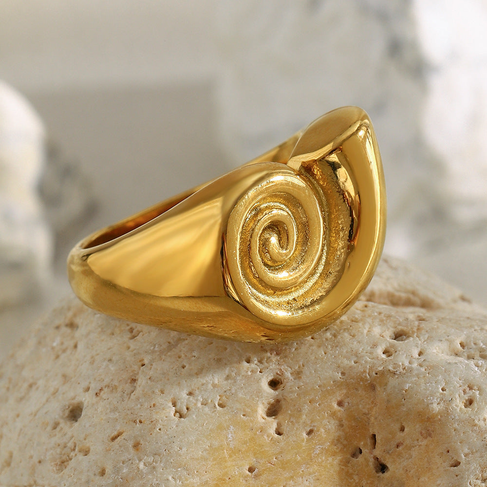 Gold plated spiral ring resting on pale stone