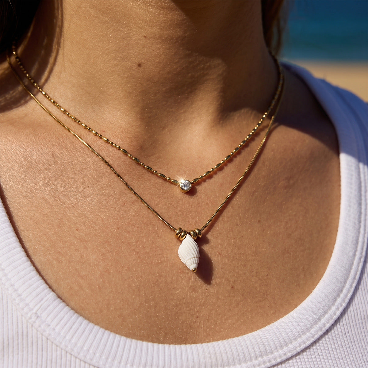Shell-shaped pendant necklace with upper clear stone chain worn on model