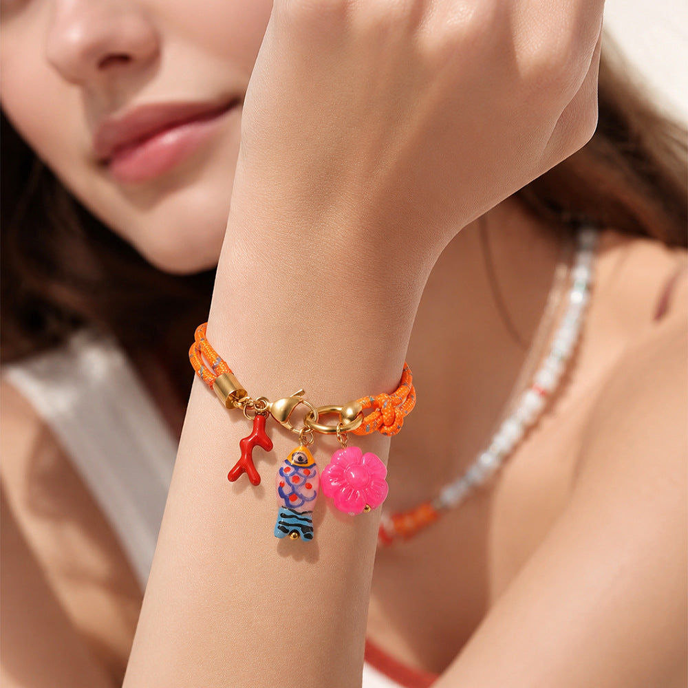 Orange double-cord charm bracelet worn on a wrist