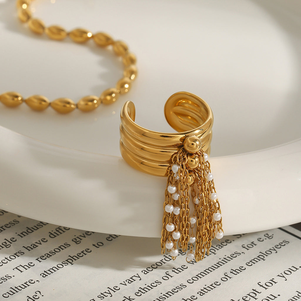 Open ring with gold chains and white bead accents on a dish