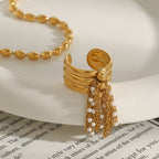 Open ring with gold chains and white bead accents on a dish