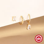 mixed rectangular stud and hoop earrings arranged on a display