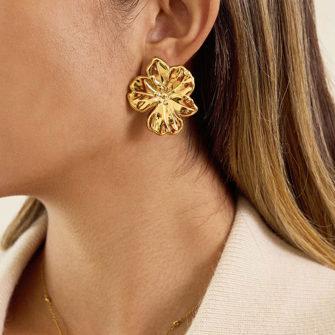 Oversized gold plated flower stud worn beside the face