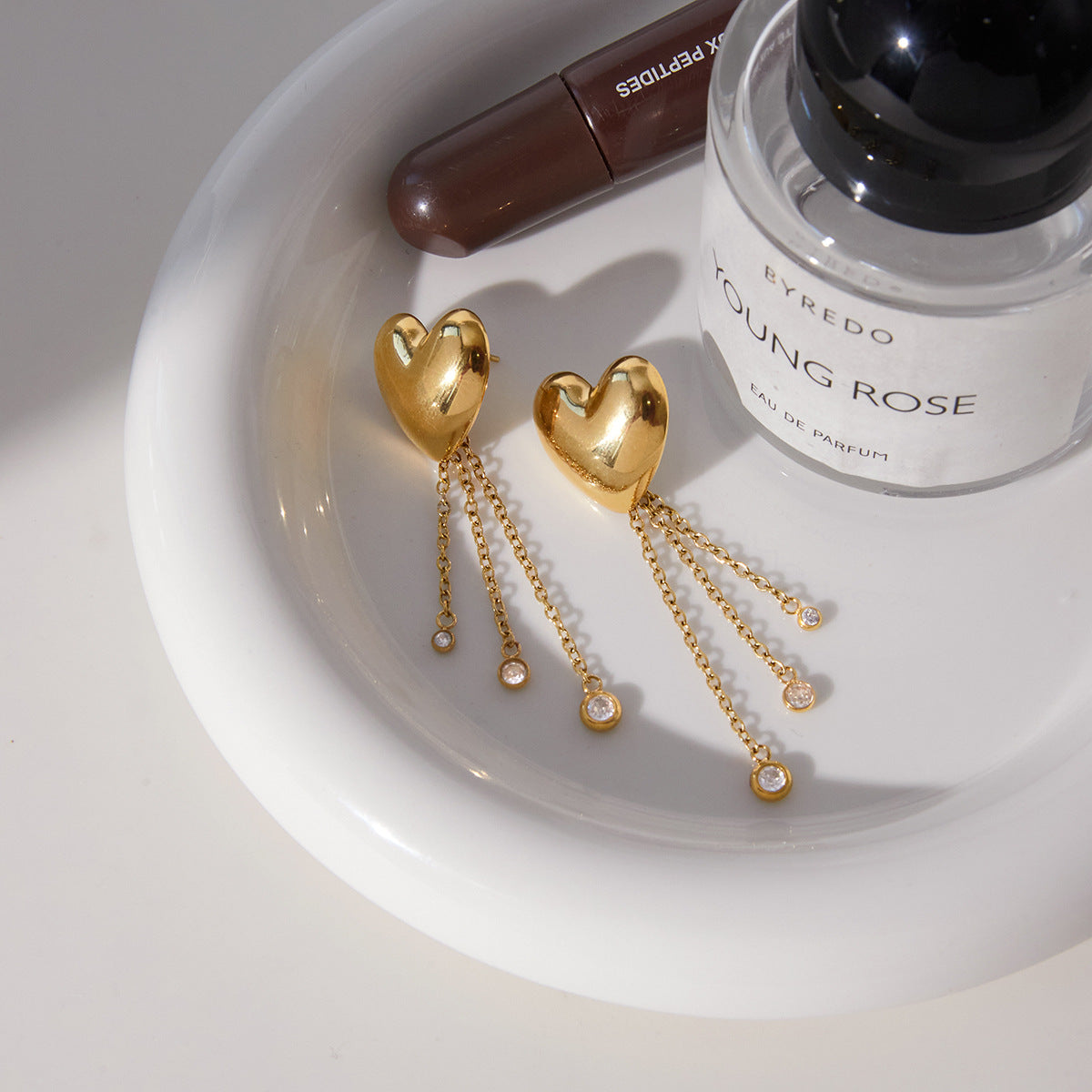 gold plated heart chain drop earrings arranged on a white tray