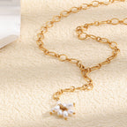 Gold plated stainless steel flower Y necklace arranged on a stone surface