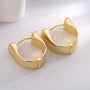 angled pair of gold plated sculpted wide huggie earrings