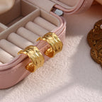 wide hammered C-hoop earrings arranged beside a jewelry case