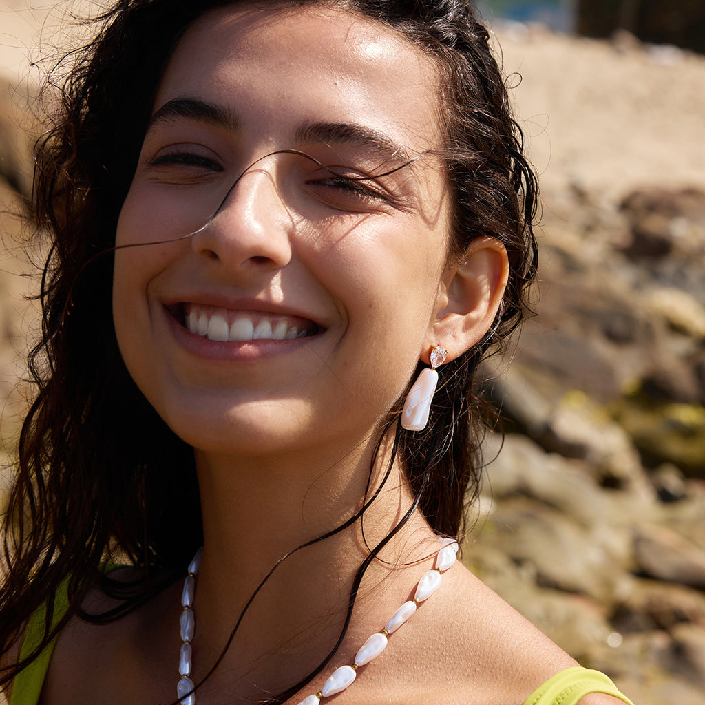 Elongated pearl-look drop earring being worn