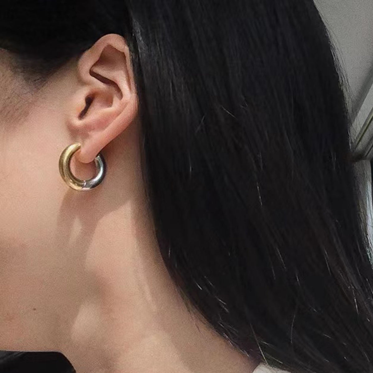 Split two-tone smooth hoop worn on an ear