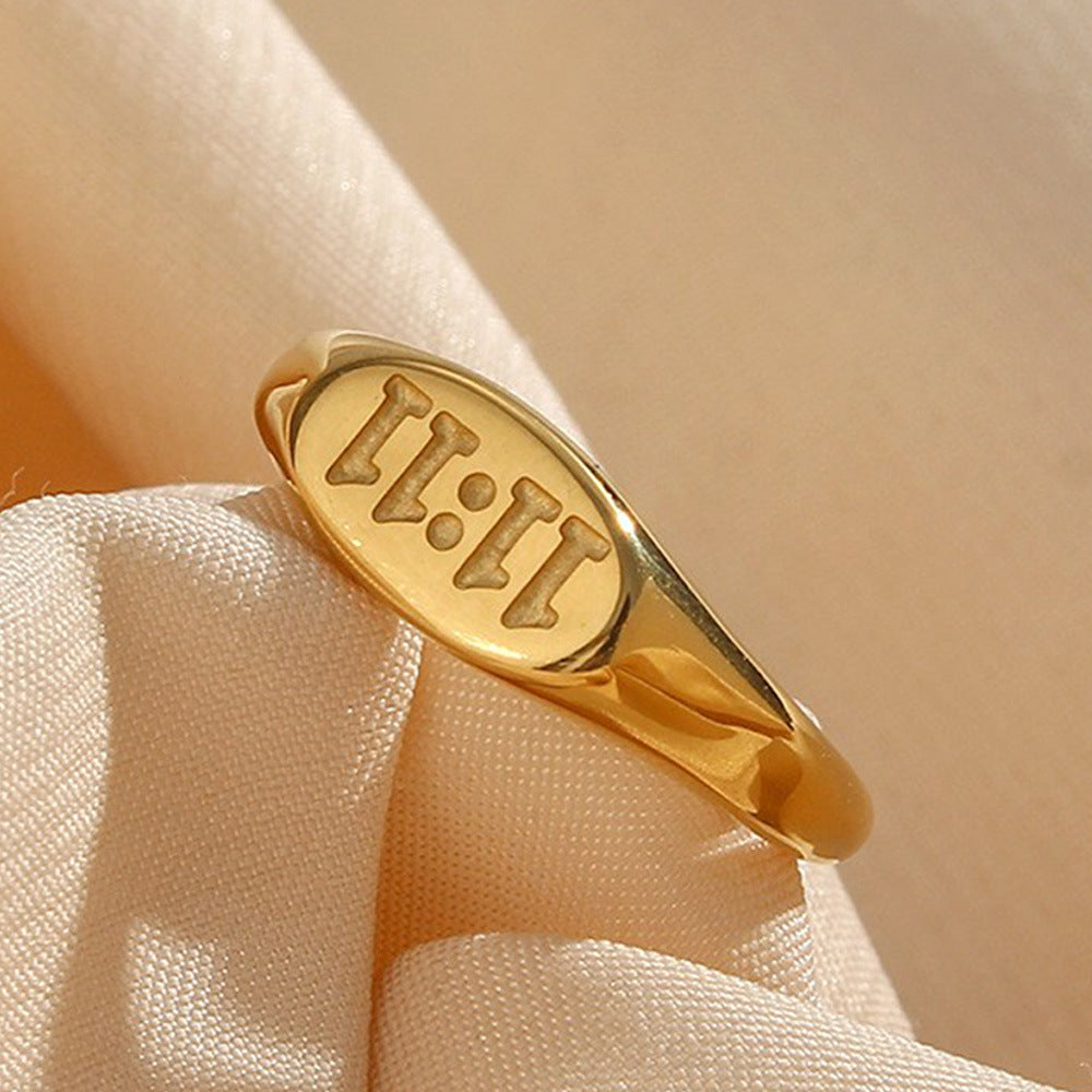 gold plated stainless steel 11:11 oval signet ring on cream fabric
