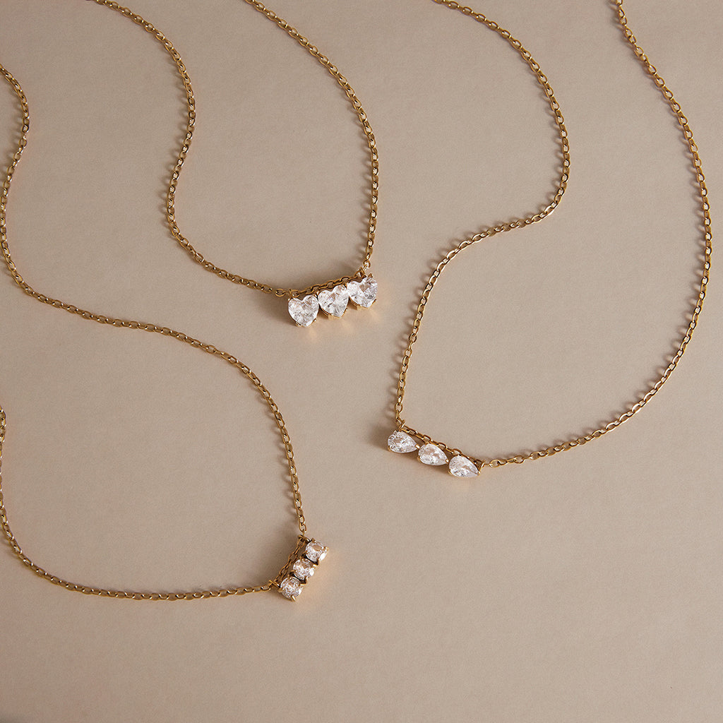 Three gold tone necklaces with different clear stone shapes
