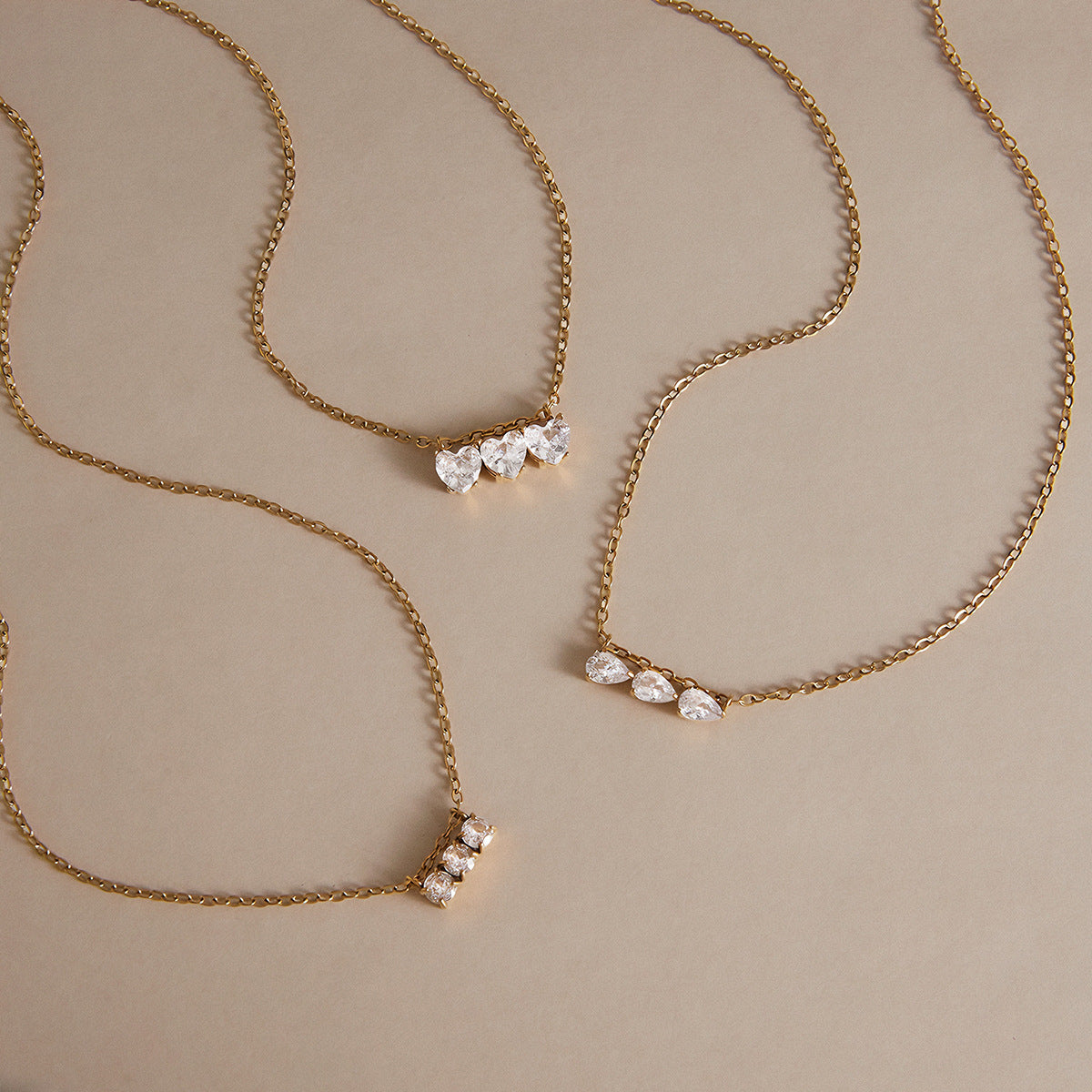 Three gold tone necklaces with different clear stone shapes