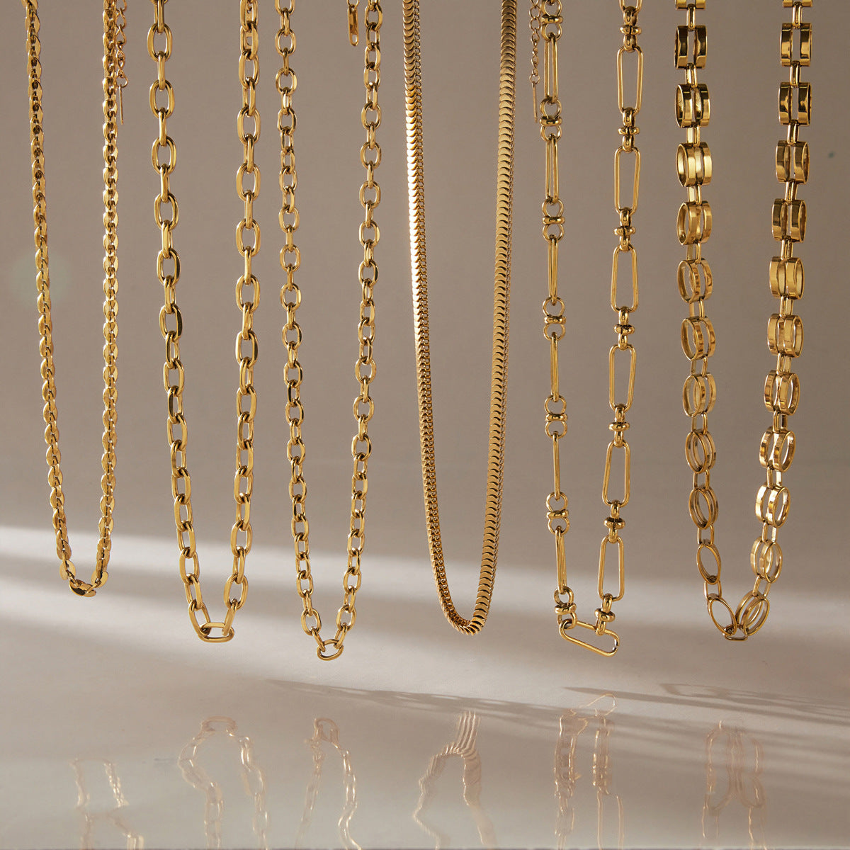 Six gold tone chain necklace profiles hanging side by side