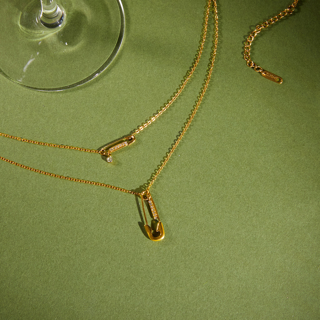 gold plated rhinestone safety pin necklace on a green surface