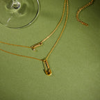 gold plated rhinestone safety pin necklace on a green surface