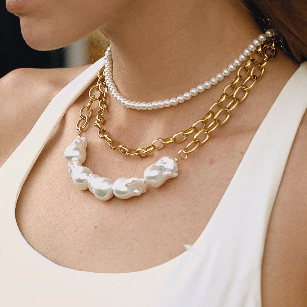 Baroque-look bead and chunky chain necklace layered on a model