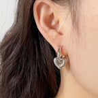 Steel color heart charm hoop earring worn on ear