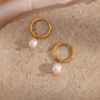 gold plated freshwater pearl drop hoop earrings on a stone surface