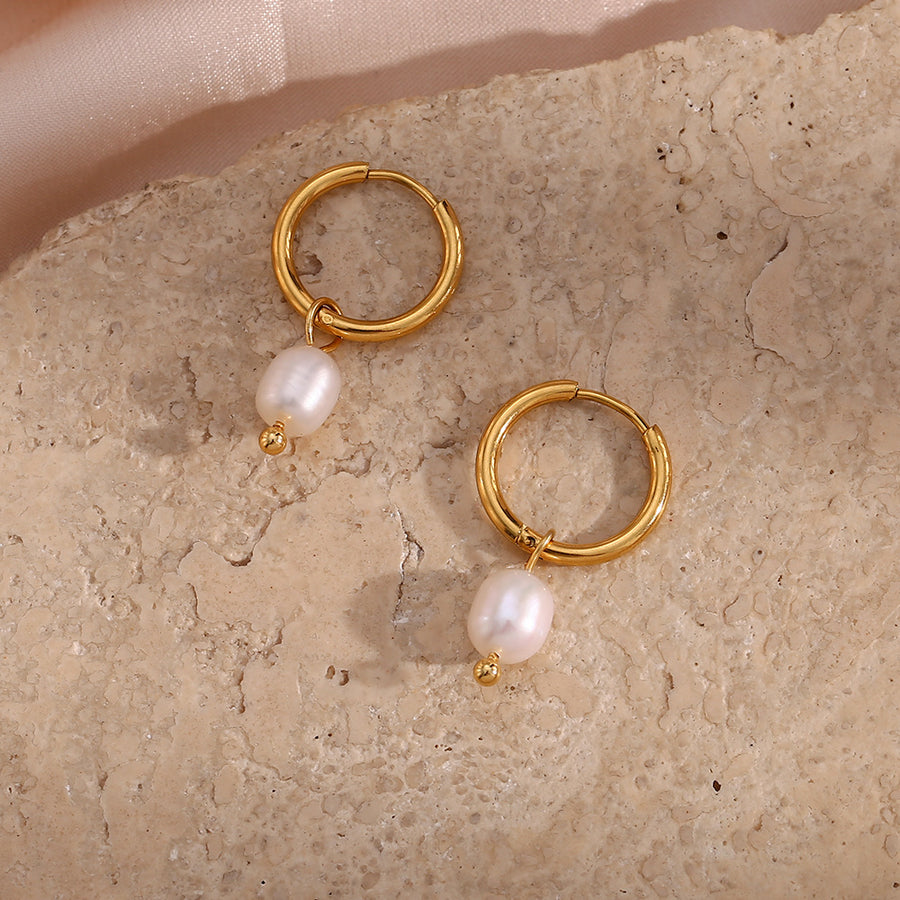 gold plated freshwater pearl drop hoop earrings on a stone surface