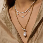 Gold tone chains and white bead necklaces worn together