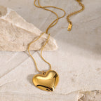 Gold-tone puffy heart necklace on pale stone