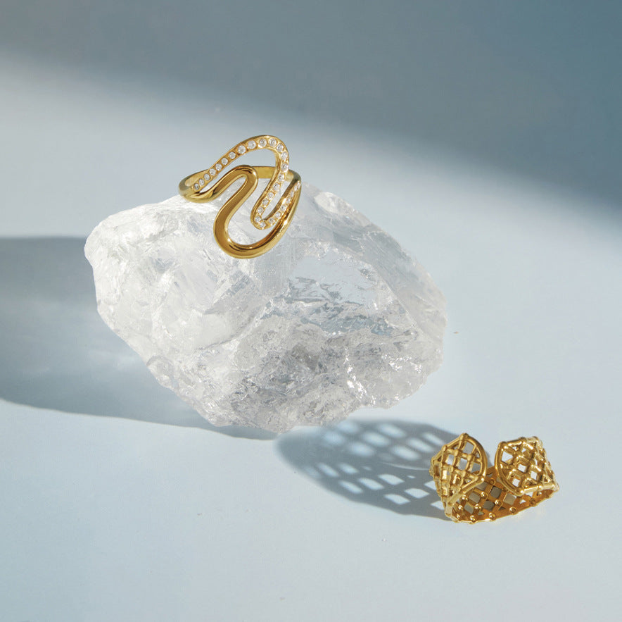 Wave and lattice rings displayed beside a clear stone