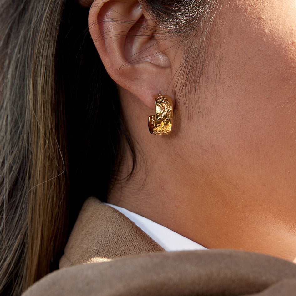 model wearing gold plated stainless steel floral relief wide hoop earrings