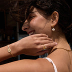White ball earrings and racket bracelet on a model