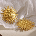 oversized gold plated sunburst earrings shown upright and flat on linen