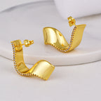 gold plated folded ribbon clear stone stud earrings in a standing studio view