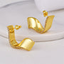 gold plated folded ribbon clear stone stud earrings in a standing studio view