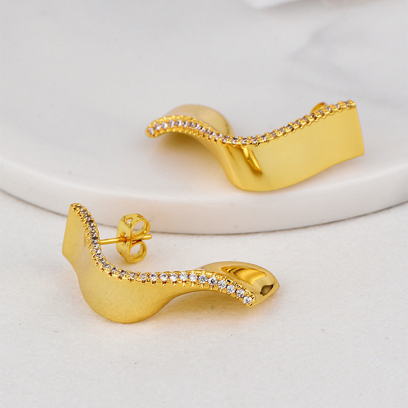mirrored sculptural stud earrings with clear stones along the curved edge