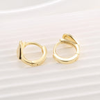 heart huggie earrings resting on a pale ribbed display