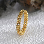 upright view of interwoven polished bead ring on a pale surface