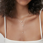 model wearing a layered snowflake and shell pearl drop necklace