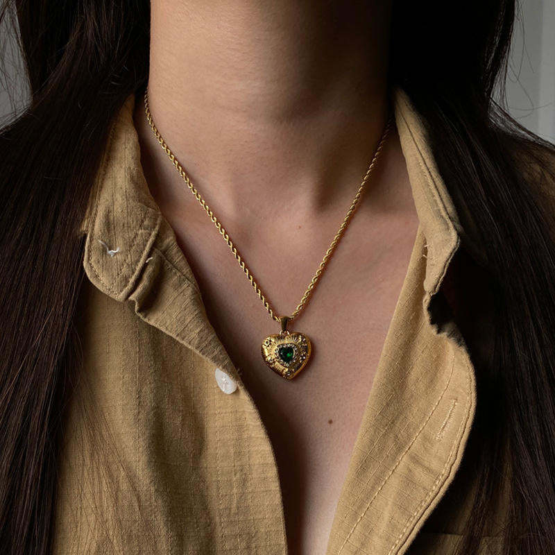 Gold-tone green heart pendant stainless steel necklace worn at the collar