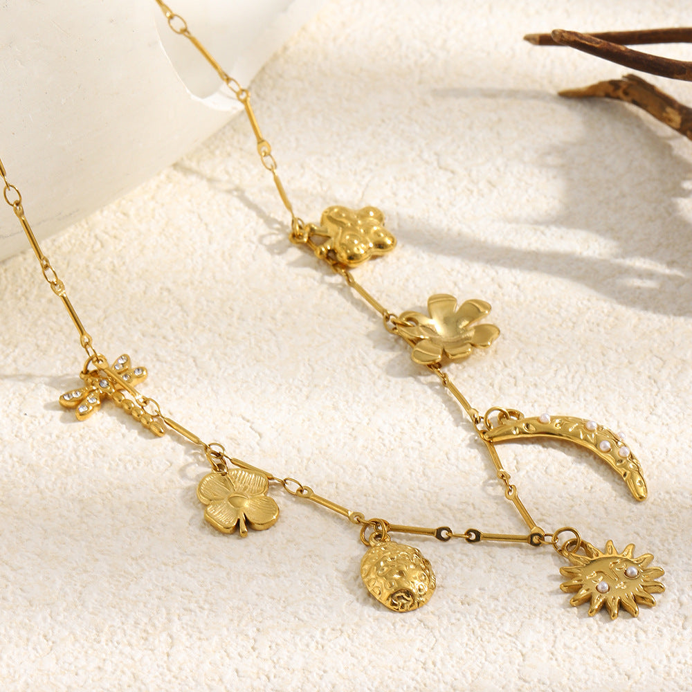 gold plated moon and flower charm necklace arranged on a textured surface