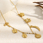 gold plated moon and flower charm necklace arranged on a textured surface