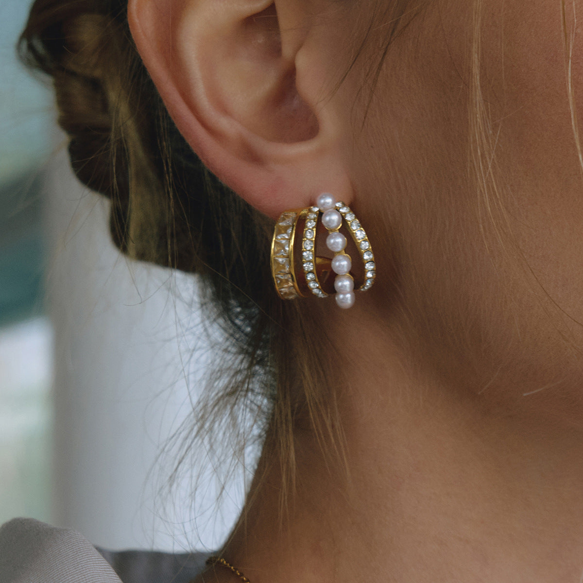 Multi-row faux pearl and clear stone hoop earring shown in a close wearing view