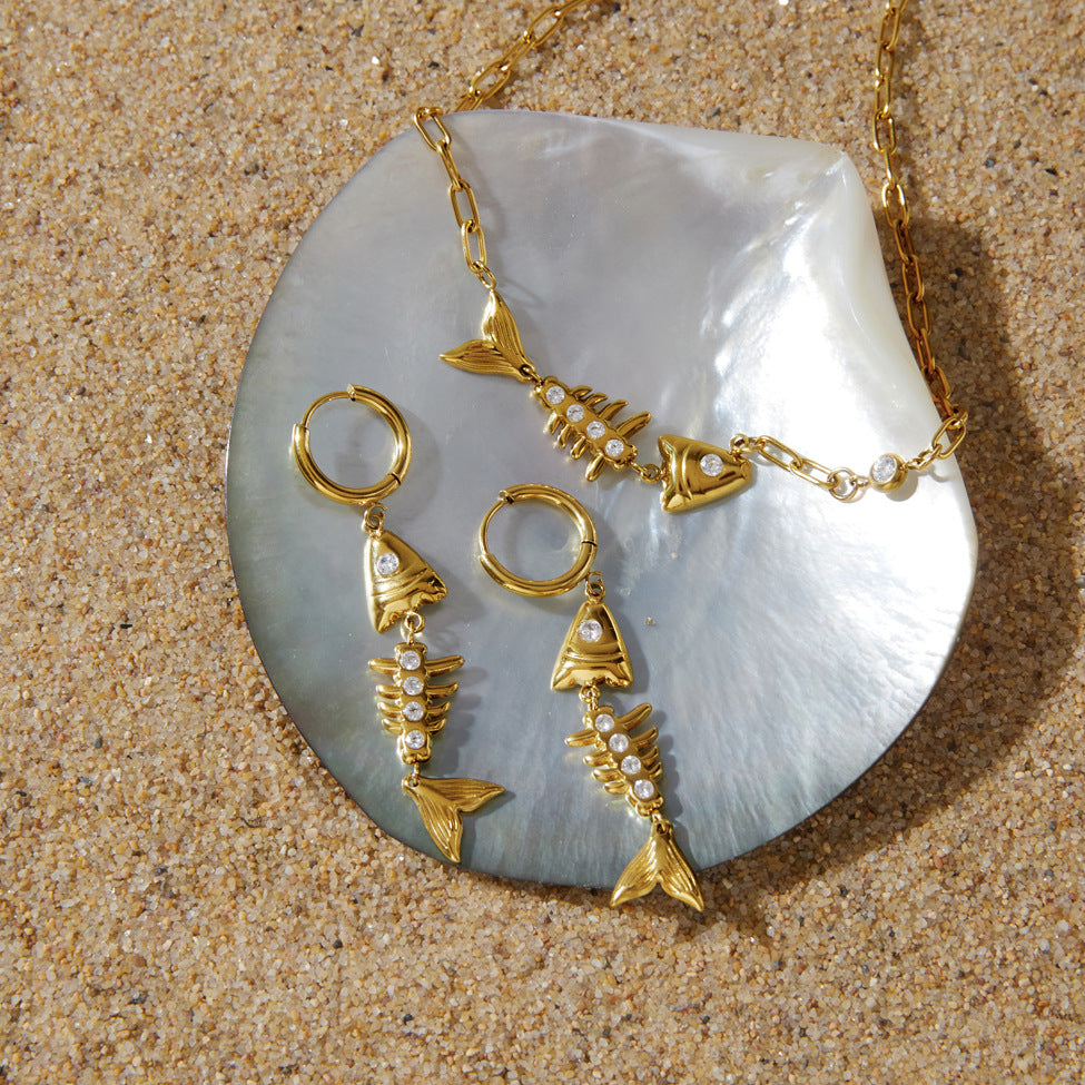 Coordinating fishbone necklace and earrings displayed on shell