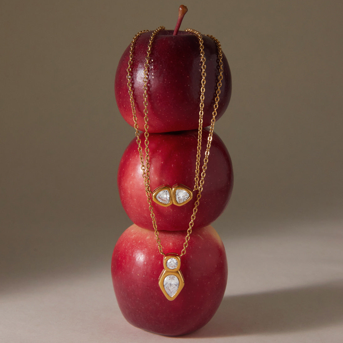 Both pendant designs displayed on stacked red apples