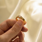 White oval accent ring shown between fingers