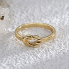 front angle of polished knot band ring on a pale crystal surface