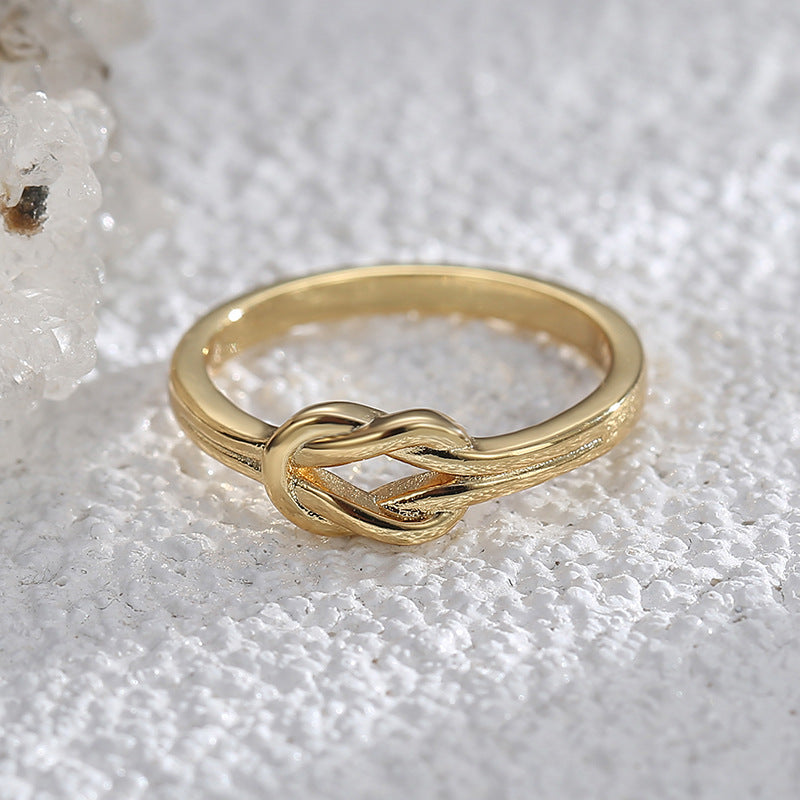 front angle of polished knot band ring on a pale crystal surface
