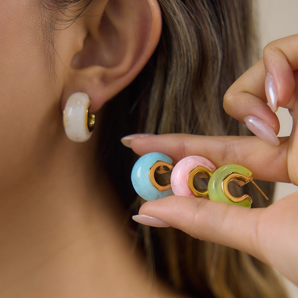 Colored resin hoops held beside a white hoop worn on the ear