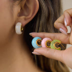 Colored resin hoops held beside a white hoop worn on the ear