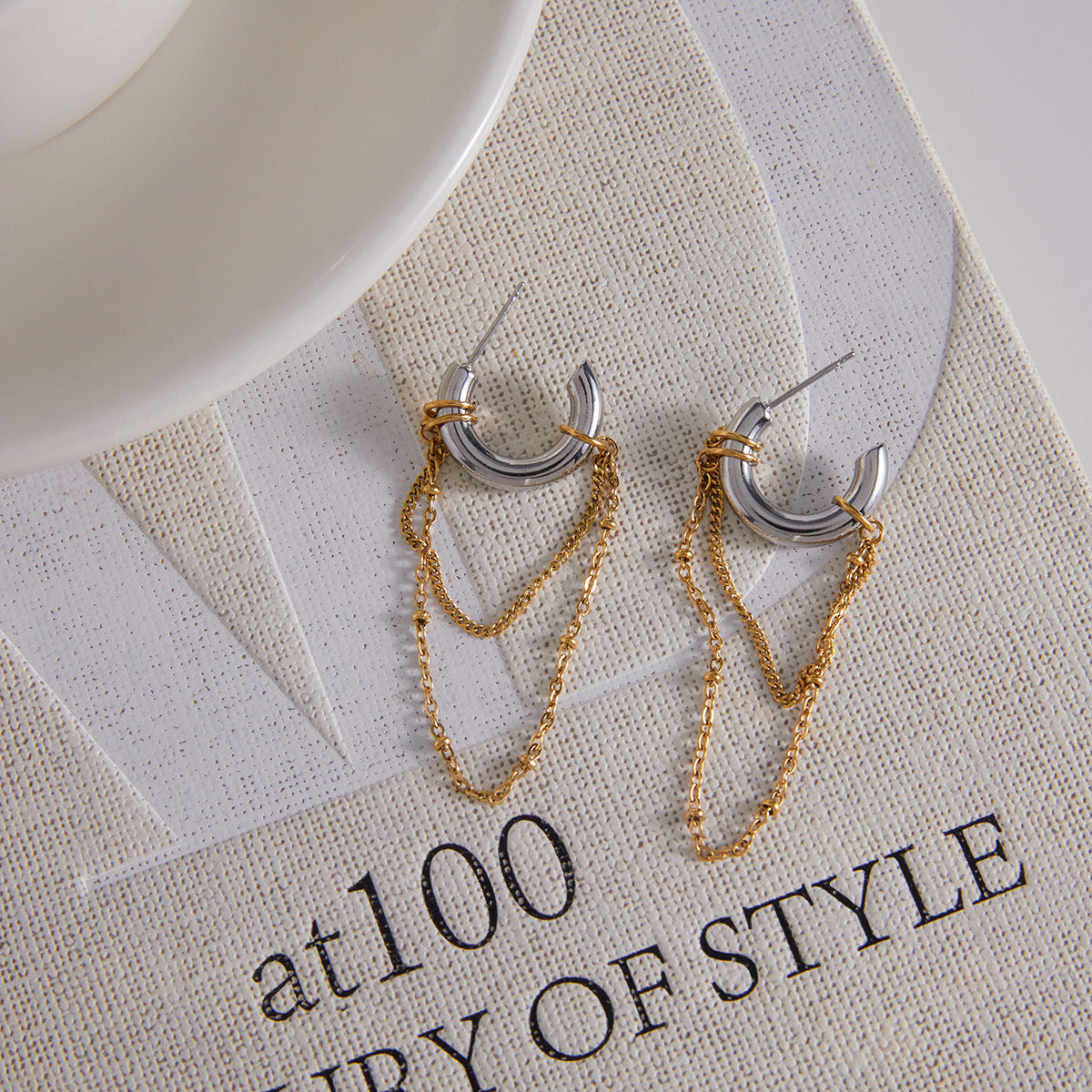pair of two-tone chain tassel hoop earrings on fabric