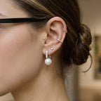 model wearing silver-finish resin pearl huggie earrings