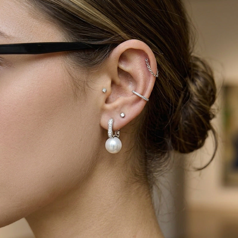 model wearing silver-finish resin pearl huggie earrings